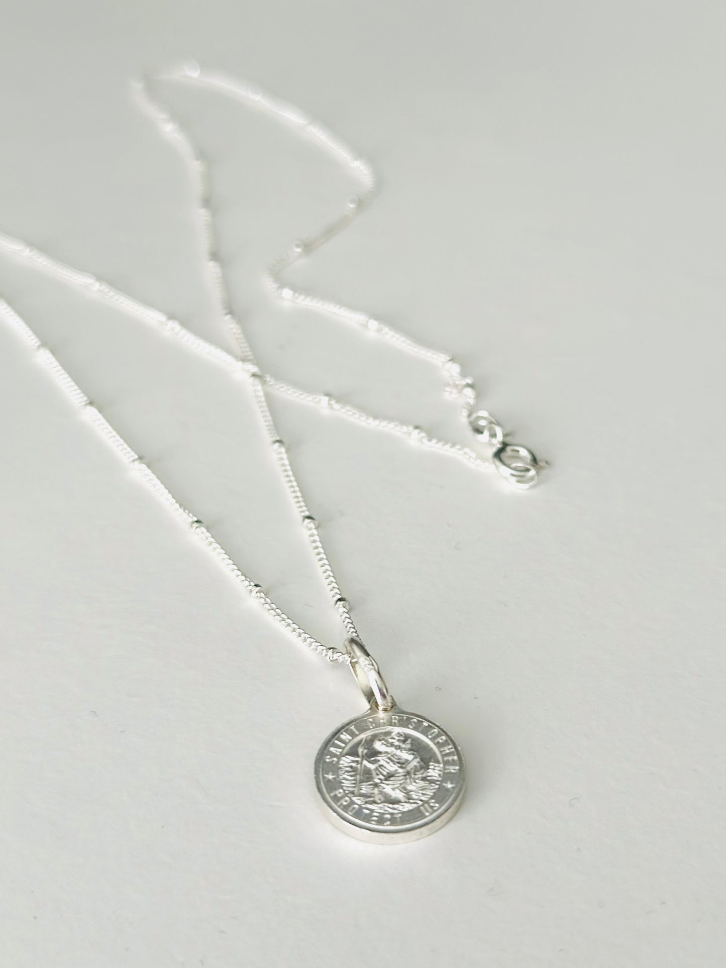 Silver necklace with a round pendant on a light gray background